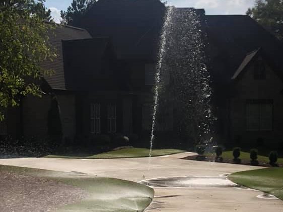 Home with irrigation system in front of it